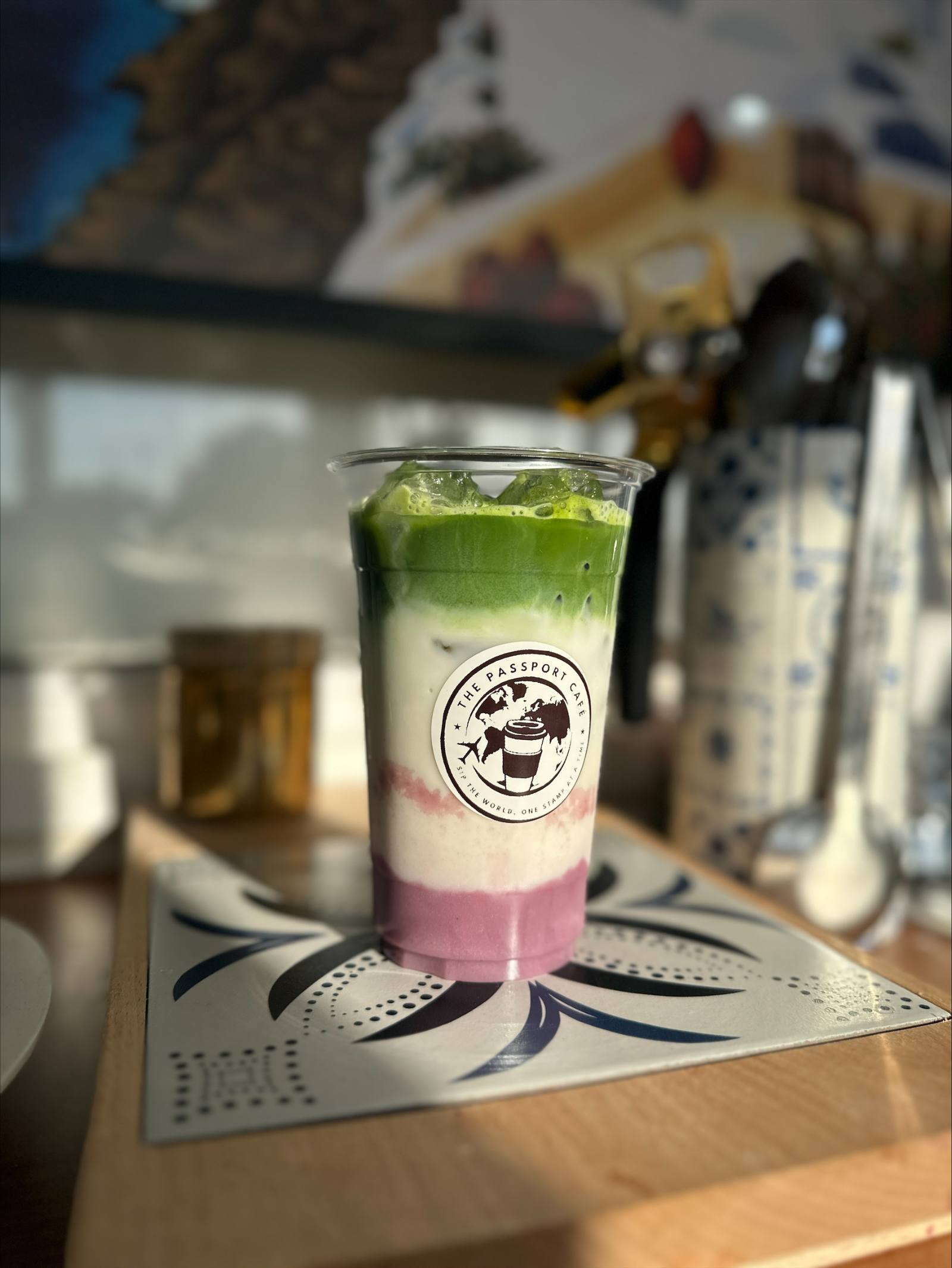 A layered iced matcha drink in a Passport Cafe cup