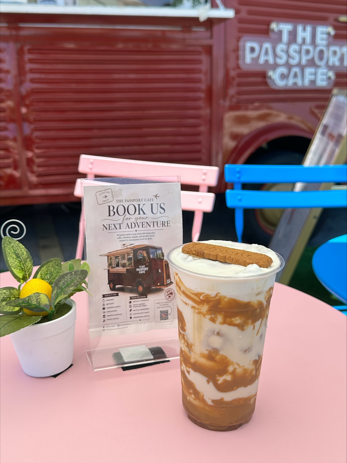 A Book Us for Your Next Adventure card on a pink bistro table beside a caramel drink